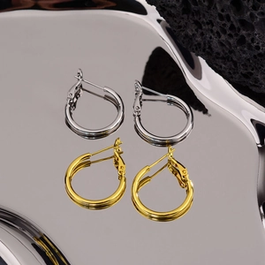Minimalist large hoop earrings in gold and silver finish on a sleek mirror background