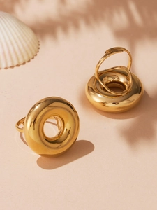 Detailed view of chunky hollow gold rings on a beach-themed background with shadows