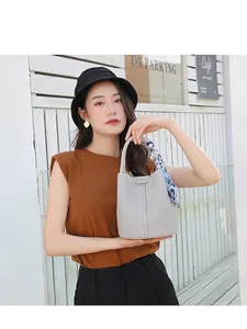 Light gray pebbled leather bucket bag with silk scarf handle and vertical stitching
