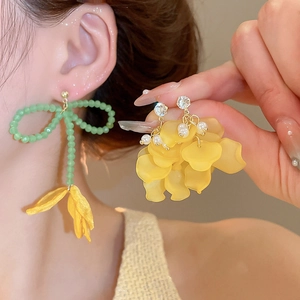 Dettaglio di orecchini a nappa floreale con fiocchi di perle verdi e petali gialli