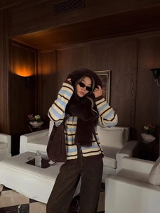 Detail of soft ice cream colored striped knitted cardigan with faux fur hooded muffler