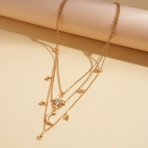 Detailed close-up of layered gold necklace featuring rhinestone star and moon pendants