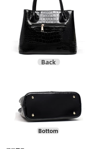 Detail view of the black crocodile pattern handbag with gold zipper and protective bottom studs
