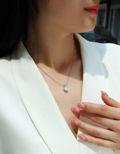 Detail of minimalist silver necklace with round moissanite pendant on female neck
