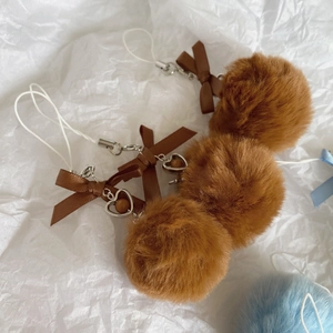 Detailed view of dark brown faux fur pom pom with satin bow and heart charm pendant