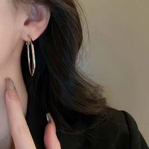 Close-up of minimalist silver hoop earrings on model highlighting a sleek metallic finish