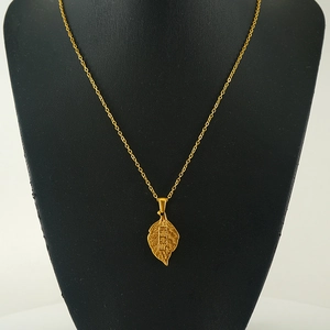 Detail of gold leaf necklace with engraved Chinese characters on a black display