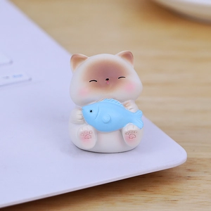 Cute mini cat figurine holding a blue fish for desktop or car dashboard decoration
