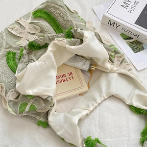 Gros plan sur la broderie florale en dentelle verte et les franges d'un sac à bandoulière