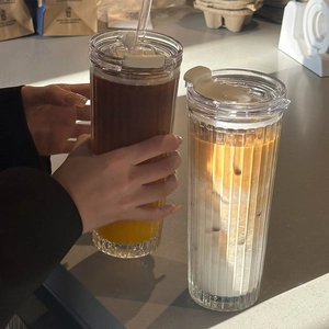 Detailed close-up of ribbed texture glass tumblers with straws in a cafe sunlight setting