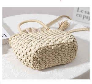 Close-up of beige woven straw beach bag with wooden bead tassels and drawstring lining