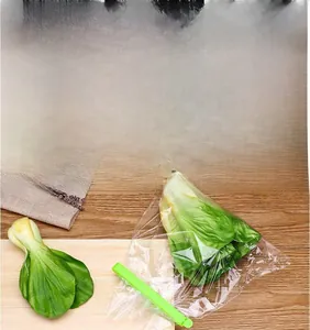 Green PP food sealing clip being used on a plastic bag of fresh greens on a wooden board