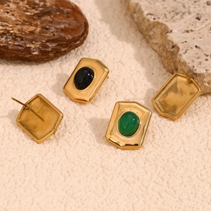 Macro shot of gold-plated geometric stud earrings with green and black oval inlays