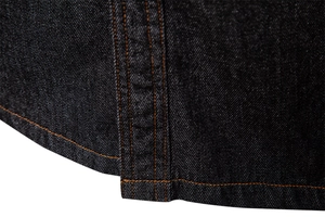 Détail macro de l'ourlet d'une chemise en jean avec surpiqûres orange sur tissu bleu marine foncé