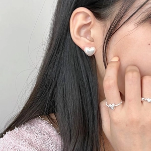 Detail of 925 sterling silver heart pearl studs and matching rope ring on model