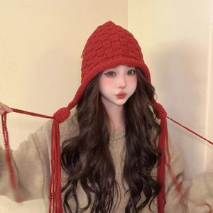 Detail view of red knitted elf hat with braided tassels and chunky knit texture