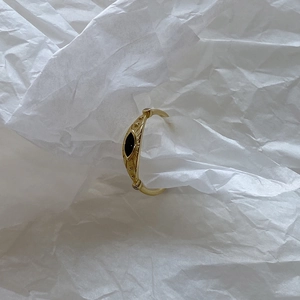 Macro view of gold-plated vintage ring featuring a black eye stone and zircon accents