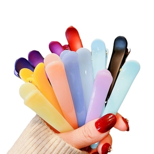 Colorful plastic hair clips set in yellow, blue and pink held against white background