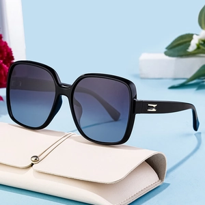 Square polarized sunglasses for women with black frames and gradient lenses on a white case