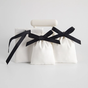 Close-up of elegant white velvet jewelry pouches with black ribbon bows for storage