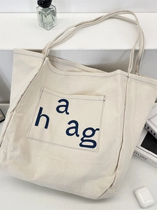 Minimalist cream canvas tote bag with haag blue logo and front pocket for commute