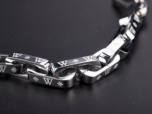 Macro view of silver titanium steel chain links with engraved patterns and a snowflake icon