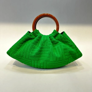 Detail of green terry cloth pleated handbag with brown round wooden handle on white background