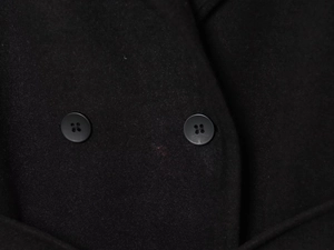 Detailed close-up of double black buttons on soft textured wool fabric of the casual coat