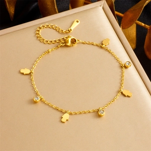 Detail van vergulde kettingarmband met Hamsa-handhangers en heldere zirkonia steen