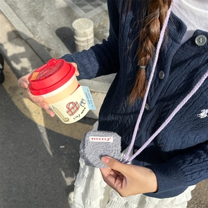 Close-up of gray plush mini earphone pouch with purple neck strap worn over a sweater