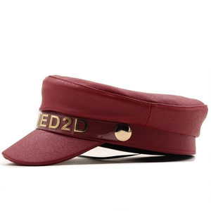 Dettaglio ravvicinato di un berretto da strillone in pelle PU bordeaux con logo dorato