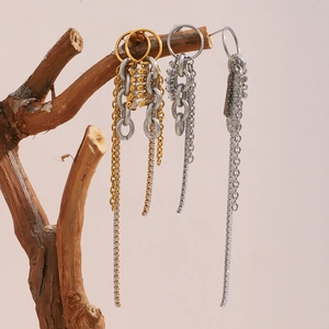 Elegant 18K gold and silver tassel earrings with zircons on a natural wood branch