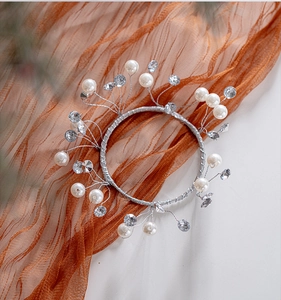 Detail of silver wire headband with white pearls and crystals on orange tulle backdrop