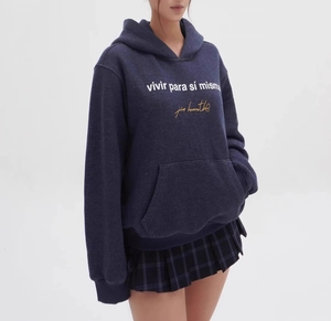 Close-up of navy blue hoodie with white Spanish typography and pleated plaid skirt texture