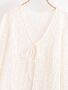 Detail of V-neck drawstring closure and textured fabric on a cream summer top