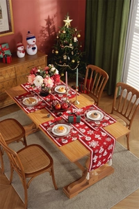 Close-up of red Christmas table runner with white snowflake patterns and fringe tassels