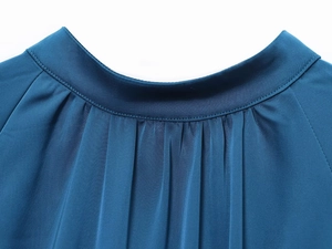 Detail of high neck pleated satin midi dress in teal with refined stitching and silk texture