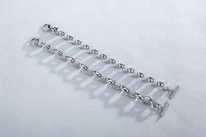 Close-up of silver titanium steel chain bracelets with toggle clasp on textured surface