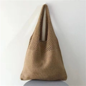Detail view of the dark brown knitted tote bag showing intricate hollow patterns and wide strap
