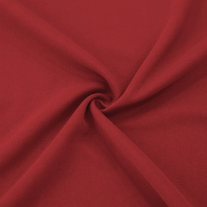Close-up of deep red knitted fabric showing spiral pleats and soft texture detail