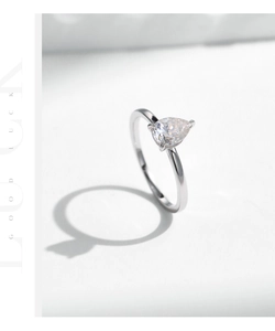 Macro detail of pear cut moissanite ring with three-prong setting and polished silver band