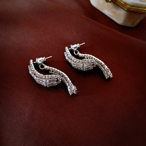 Macro shot of silver drop earrings with baguette and round zircons on red silk