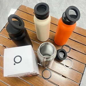 Four 304 stainless steel insulated water bottles with ring handles on a dark wood table