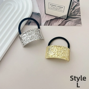 Detail of L-style hair tie featuring gold and silver hammered metal plates on minimalist tray