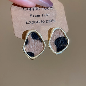 Macro shot of 100% copper earrings featuring leopard print patterns and golden frames