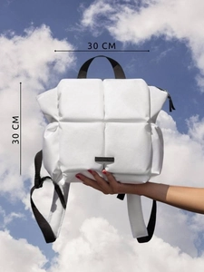 Détail macro d'un sac à dos blanc matelassé avec des dimensions de 30 cm sur ciel bleu