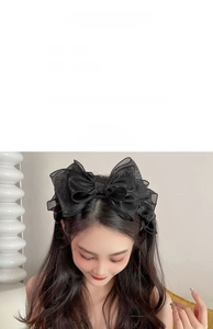 Detailed view of large black mesh bow headband with soft layered texture on model