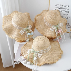 French country straw sun hat with lace bow and tulip charm shown on a white table