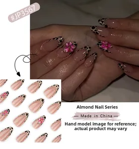 Detail of almond-shaped fake nails with leopard print tips and 3D pink flower accents