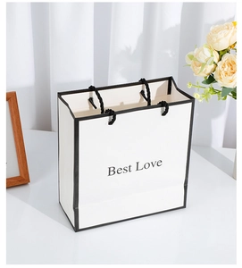 Detail of white paper gift bag with black trim, black handles and Best Love lettering